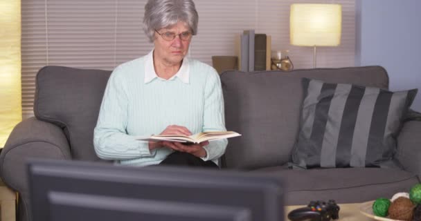 Elderly Woman Chooses Videogames Reading Book — Stock Video