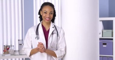 Başarılı siyahi kadın doktor ofiste gülümsüyor.