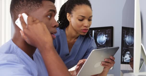 两名非洲裔美国医生用平板电脑和手机合作 — 图库视频影像