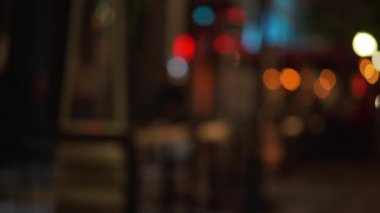 Şehir caddesindeki kaldırımın arka planında gece renk değiştiren bir plaka var. Yeşil ekran bileşimi için bulanık video arkaplanı. 4k