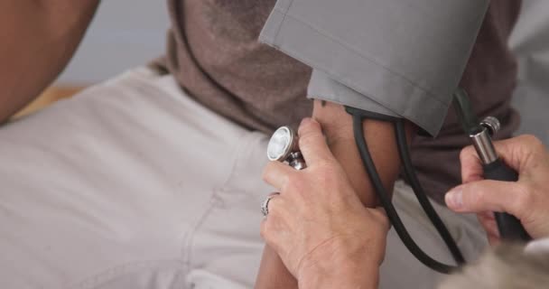 关闭医生抽吸仪表以测量病人的血压 高级医生测量年轻黑人男性血压的特写 — 图库视频影像