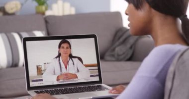 Bilgisayarda doktorla video sohbeti yapan siyahi kadın.