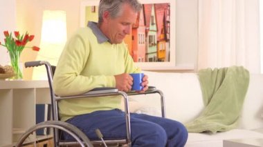 Son sınıf öğrencisi kahveyle tekerlekli sandalyede oturuyor.