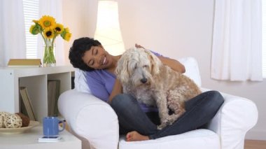 Siyahi kadın gülümsüyor ve köpeğini okşuyor