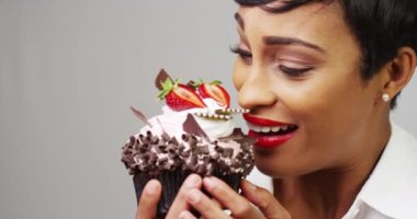 Siyah kadın süslü bir tatlı büyük bir ısırık alarak