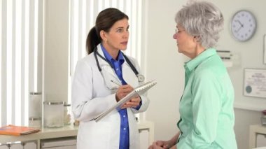 Kıdemli doktor hastayla konuşuyor ve notlar alıyor.