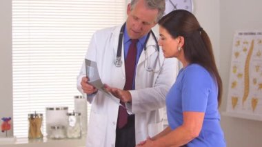 Doktor, röntgenli hastaya ameliyat prosedürünü açıklıyor.