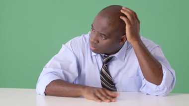 Afrika kökenli Amerikalı iş adamı masada düşünüyor.