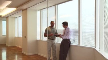 Ofis penceresinde çalışan iş adamları şehre tepeden bakıyor.