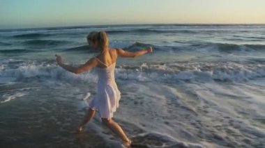 Gün batımında genç bir kadın plaj balesi