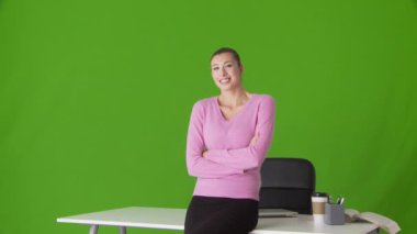 Masanın önünde kollarını kavuşturmuş genç bir iş kadını portresi.