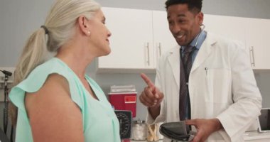 Üst düzey kadın hastalarla ilgilenen olumlu erkek doktor. Sağlık kliniğindeki yaşlı beyaz kadınla konuşan mutlu bir doktor.