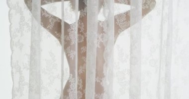 Perdenin arkasında duran çıplak siyah kadın.