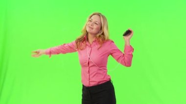 İş kadını kulaklıkla müzik dinliyor ve dans ediyor.