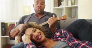 Mutlu siyah çift kanepede ukulele ile yalan
