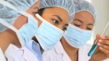 Çok ırklı kadın bilim adamlarından oluşan bir ekip bir testte maddeyi analiz ediyor.