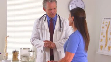 Erkek doktor hastanın ilaçlarla ilgili sorular sormasını dinliyor.
