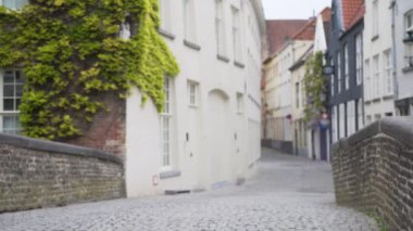 Bruges 'de kaldırım taşı caddesindeki köprünün arka planındaki alçak açı. Motosikletli bulanık adam. 4k