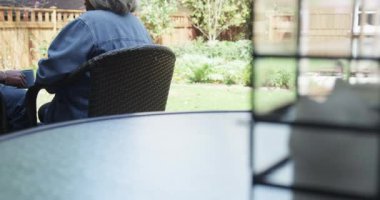 Mutlu siyah çift verandada oturup kahve içerek konuşuyor.