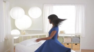 Afrikalı Amerikalı kız dans ediyor ve yatakta zıplıyor.