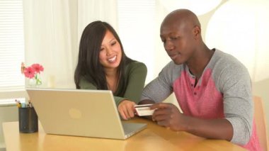 Afrikalı Amerikalı ve Asyalı çift online alışveriş yapıyor.