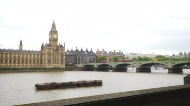Thames Nehri 'nin yavaş yatay tepsisi ve Londra şehir manzarası toprak setten, Big Ben arka planda. Thames Nehri manzarasının dışında, köprüden geçen Londra otobüsleri. 4k
