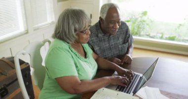 Üst düzey siyah çift online bankacılık yapmak için dizüstü bilgisayar kullanıyor.