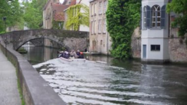 Bruges 'deki kanal plâkasının odak noktası dışında. Tur botu birleşim için geçiyor. Avrupa 'da turistlerin bulanık video arkaplanı. 4k