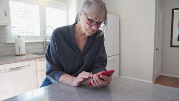 Senior Mulher Caucasiana Mensagens Texto Smartphone Enquanto Sentado Balcão Cozinha — Vídeo de Stock