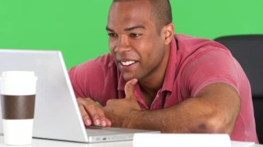 Masada dizüstü bilgisayar kullanan gülümseyen adam.