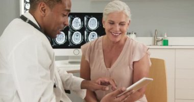 Doktor muayenehanesinde oturan sağlıklı kadın hasta beyin sarsıntısı geçiren genç doktoru dinliyor. Kafkasyalı kıdemli kadın kafa yaralanması hakkında doktora danışmanlık yapıyor.