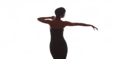 Siyah kadın beyaz arka planda ağır çekimde dans ediyor.