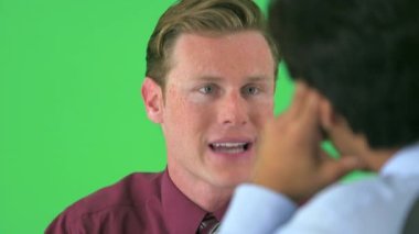 Yeşil ekranda konuşan iki iş adamının omzunun üstünden.