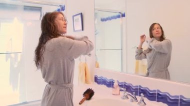 Banyoda yıkanmış saçları tarayan bir kadın.