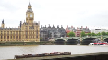 Big Ben 'in yatay tepsisi ve nehir kenarından Londra şehir manzarası. Merkez Londra 'da Thames Nehri' nden geçen teknenin odak noktası dışında. 4k