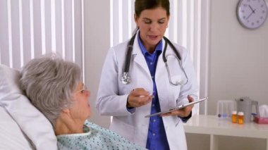 Kıdemli kadın doktor tabletli hastayla konuşuyor.