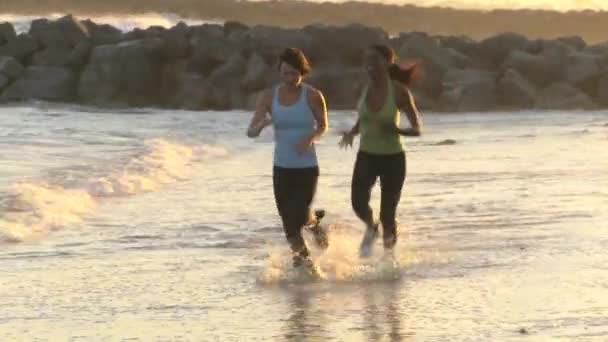 两名年轻女子在日落时沿着岸线奔跑 — 图库视频影像