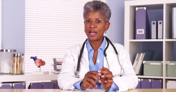 Senior African Doctor Sitting Desk Talking Camera — Stock Video