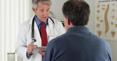 Ofiste yaşlı hasta sorular sormaya doktor