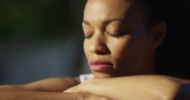 Açık havada kapalı gözlerle oturan siyah kadın