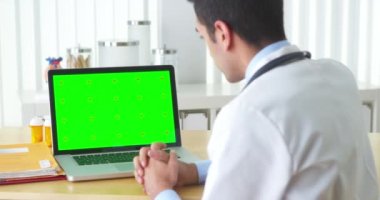 İspanyol doktor yeşil ekranlı laptopla konuşuyor.