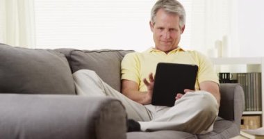 Tablet kullanan yaşlı adam gülümsüyor