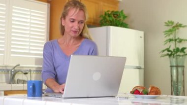 Kahve içen ve laptop kullanan olgun bir kadın.