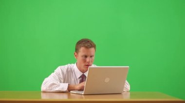 İş adamı masada oturmuş kollarını kaldırarak kutlama yapıyor.