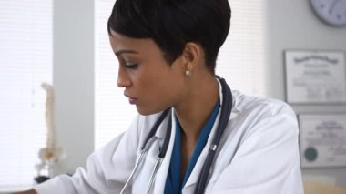 Doktor masasında çalışıyor ve notlar alıyor.