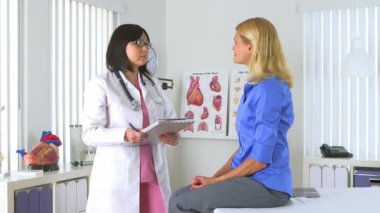 Asyalı doktor kadınların endişelerini dinliyor.