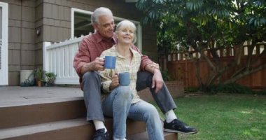 Bahçelerinde kahve içen yaşlı çift.