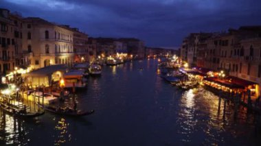 Rialto Köprüsü 'nden denize yansıyan şehrin ışıklarının muhteşem panoramik manzarası. Akşamları Grand Canal 'daki limanda renkli Venedik binaları ve tekneleri. 4k