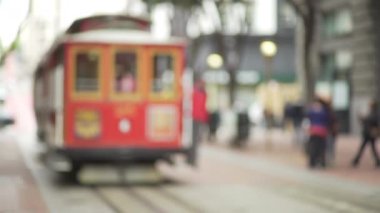 Turistlerin, San Francisco teleferiğiyle fotoğraf çekerken odak dışı görüntüsü. Şehir merkezindeki işlek caddede ikonik kırmızı tramvay. 4k