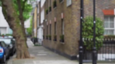 Londra, İngiltere 'de sakin bir yerleşim bölgesinde sokak köşesinin bulanık görüntüsü. İngiliz evinin önündeki kaldırımdan çekilen görüntüler arka plan olarak kullanılacak. 4k